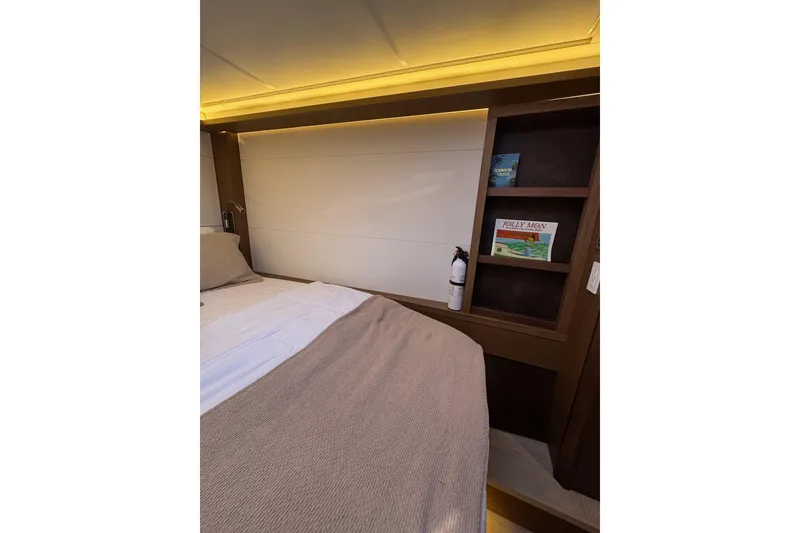 Slide: The Image of Cozy bedroom interior of 2020 Lagoon 46 yacht with books and fire extinguisher. - 34