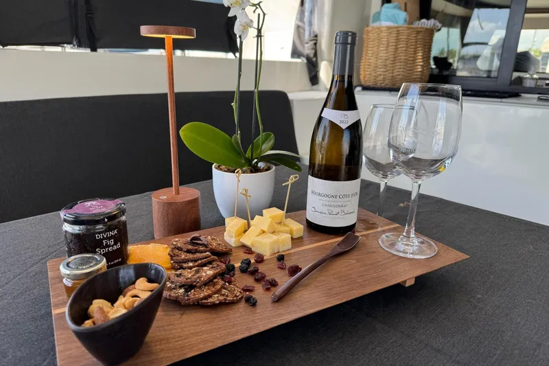 Slide: The Image of Cheese and wine setup on Lagoon 46 yacht, featuring fig spread, nuts, and Chardonnay. - 73