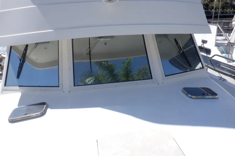 Slide: The Image of 2002 Mainship 430 Trawler with reflective windows and deck hatches in marina setting. - 15
