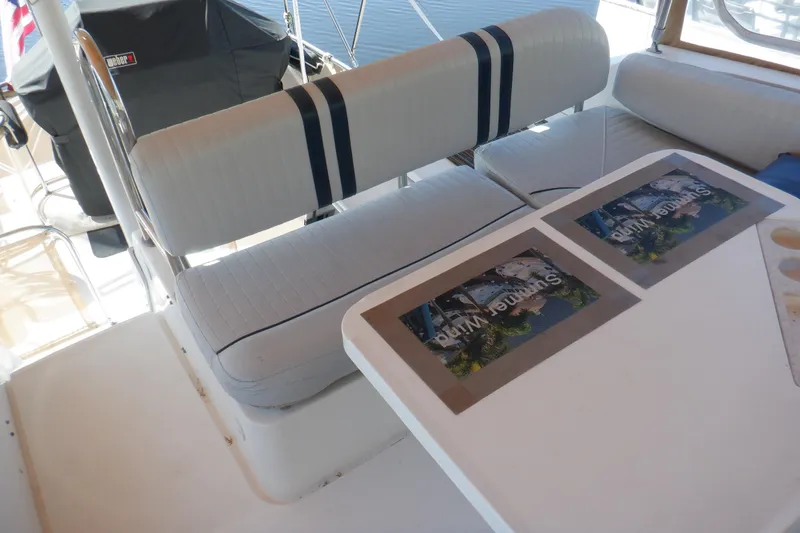 Slide: The Image of 2002 Mainship 430 Trawler interior with cushioned seating and table setup. - 23