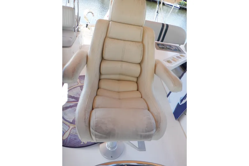 Slide: The Image of Captain's chair on 2002 Mainship 430 Trawler, featuring plush beige upholstery. - 24