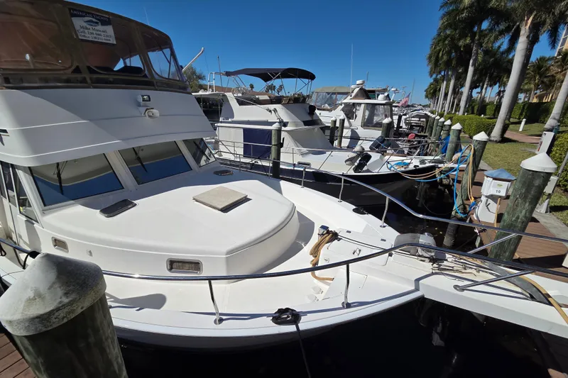 Slide: The Image of 2002 Mainship 430 Trawler docked at marina, surrounded by palm trees and clear blue sky. - 3