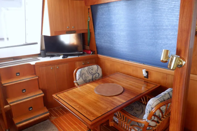 Slide: The Image of Interior of 2002 Mainship 430 Trawler with wooden dining area and TV. - 32