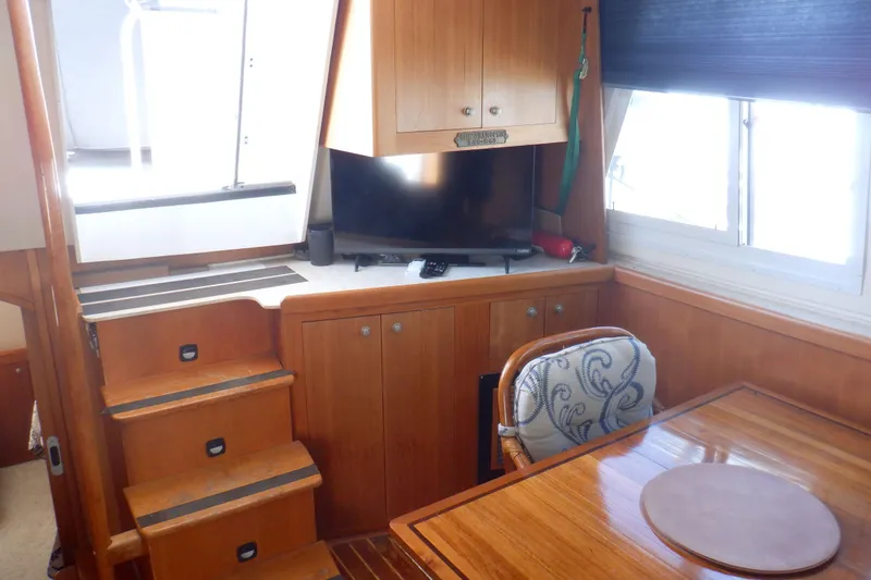 Slide: The Image of 2002 Mainship 430 Trawler interior with wooden cabinetry, TV, and dining area. - 33
