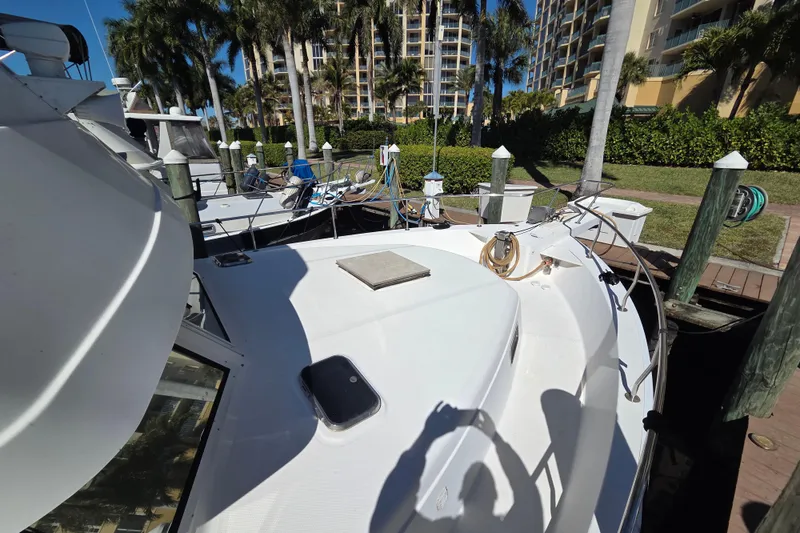 Slide: The Image of 2002 Mainship 430 Trawler docked near palm trees and waterfront buildings. - 4