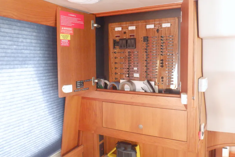 Slide: The Image of Electrical panel inside a 2002 Mainship 430 Trawler, featuring circuit breakers and warning labels. - 42