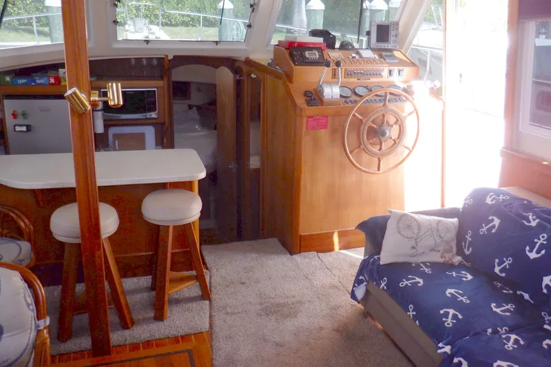 Slide: The Image of Interior of 2002 Mainship 430 Trawler with helm, seating, and nautical decor. - 44