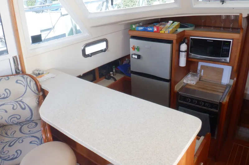 Slide: The Image of 2002 Mainship 430 Trawler kitchen with countertop, fridge, microwave, and stove. - 50
