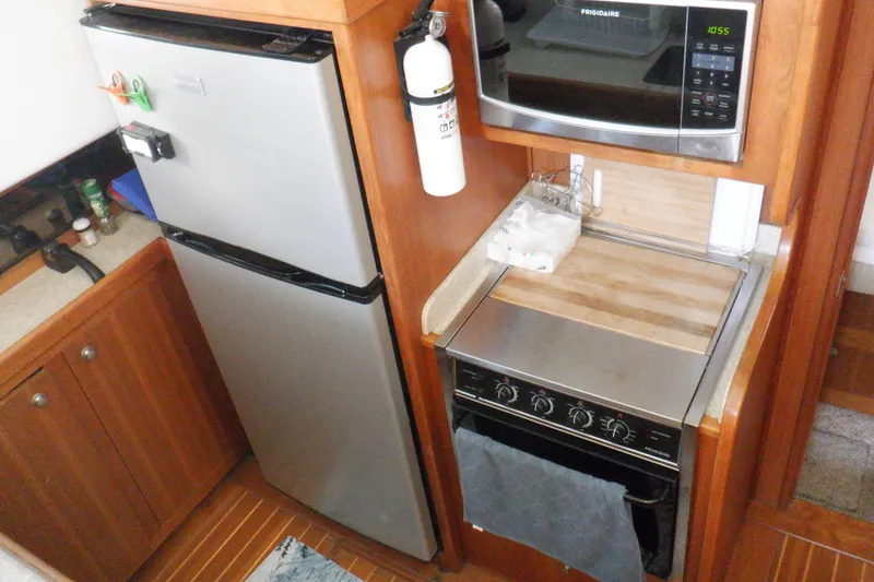 Slide: The Image of 2002 Mainship 430 Trawler kitchen with fridge, microwave, and stove in compact layout. - 51