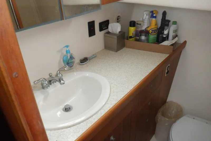 Slide: The Image of Bathroom sink area on a 2002 Mainship 430 Trawler with cleaning supplies. - 57