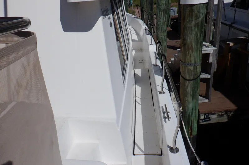 Slide: The Image of 2002 Mainship 430 Trawler docked, showcasing side deck and railing details. - 6