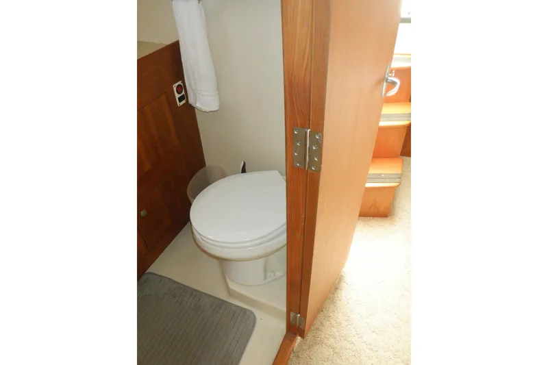 Slide: The Image of 2002 Mainship 430 Trawler bathroom with wooden door and white toilet. - 66