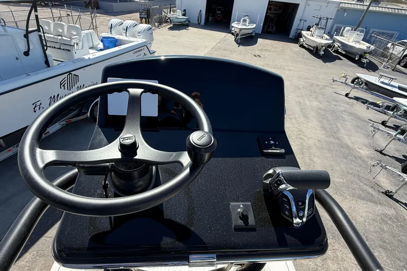 Slide: The Image of 2026 Pathfinder 2600 TRS boat helm with steering wheel and controls in a marina setting. - 16