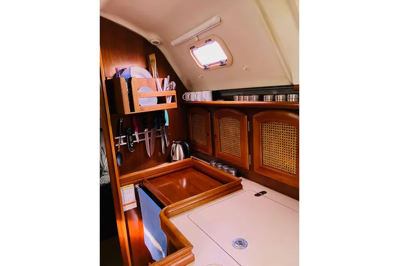 Slide: The Image of Cozy kitchen area in a 1998 Beneteau 381 sailboat with wooden cabinetry and utensils. - 24