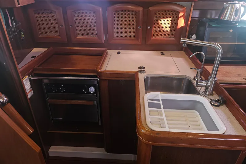 Slide: The Image of 1998 Beneteau 381 yacht kitchen with wooden cabinets, sink, and stove. - 25