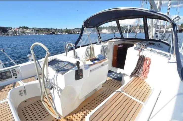 Slide: The Image of 1998 Beneteau 381 sailboat cockpit with wooden deck, steering wheel, and marina view. - 9