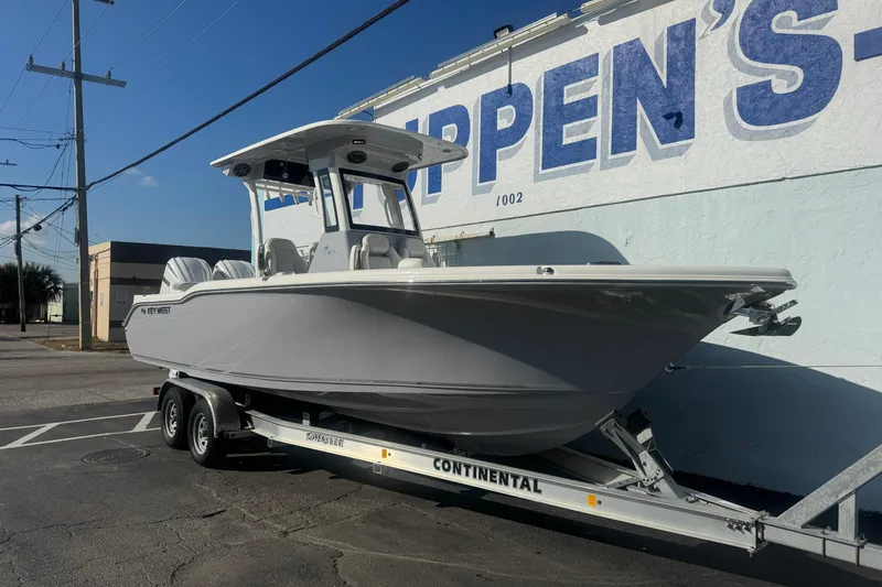 Slide: The Image of 2026 Key West 263 FS boat on trailer, parked beside a building. - 2