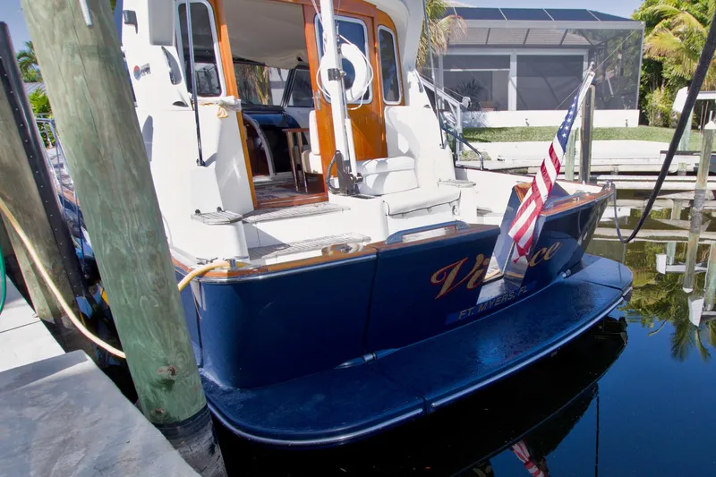 Slide: The Image of 2001 Linssen DS 45 yacht docked, displaying American flag, with polished wood accents. - 79