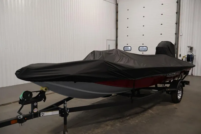 Slide: The Image of 2024 Tracker Pro Team 175 TXW boat covered in black tarp, stored indoors. - 43