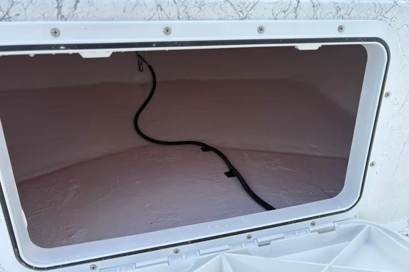 Slide: The Image of Open storage compartment in 2026 Coastal Skiff 171 boat, featuring a visible cable inside. - 13