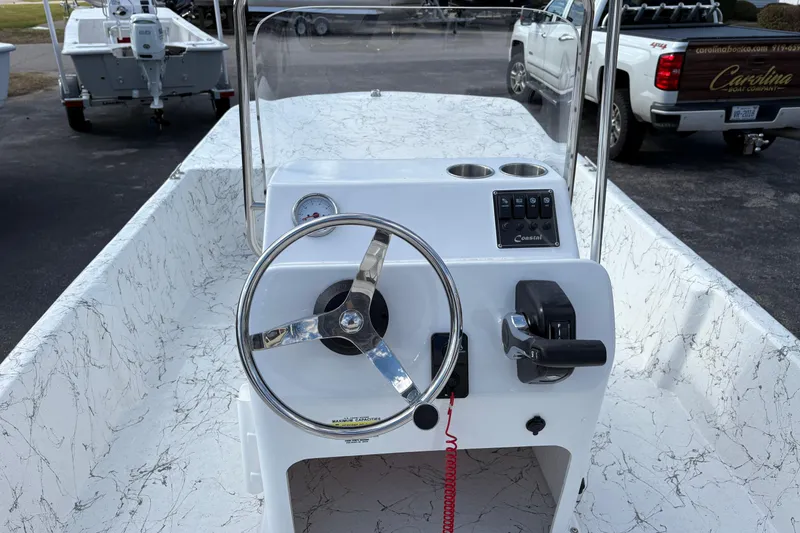 Slide: The Image of 2026 Coastal Skiff 171 boat console with steering wheel and controls, parked outdoors. - 8