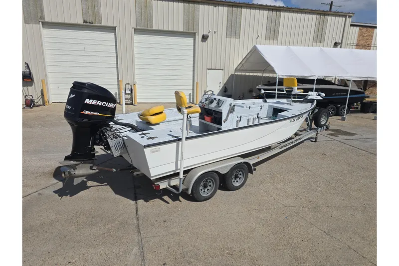 Slide: The Image of 2011 Reno Skiff 22 boat on trailer with Mercury outboard motor, parked outside a garage. - 3