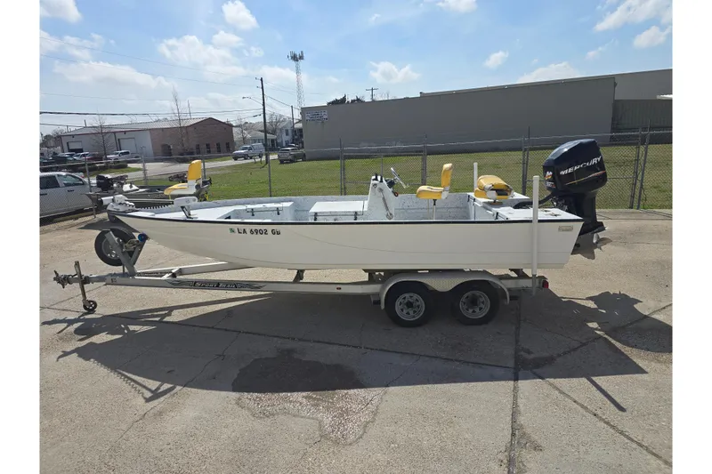 Slide: The Image of 2011 Reno Skiff 22 boat on trailer with Mercury outboard motor, parked outdoors. - 6