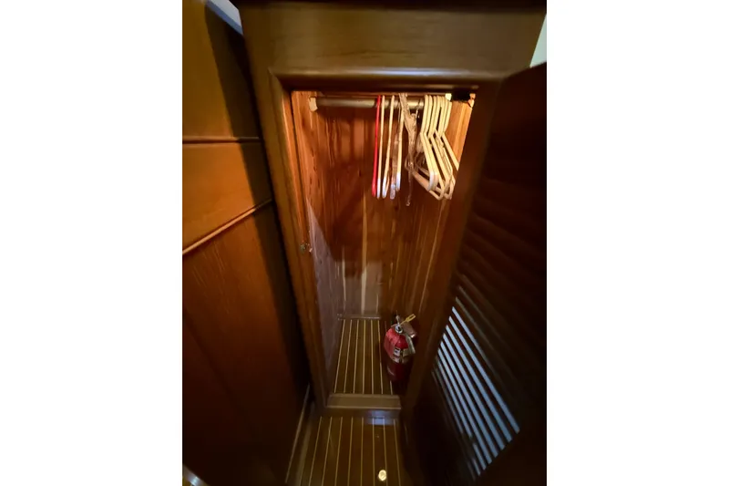 Slide: The Image of Wooden closet interior on 2000 Grand Banks 43 Eastbay FB yacht with hangers and fire extinguisher. - 112