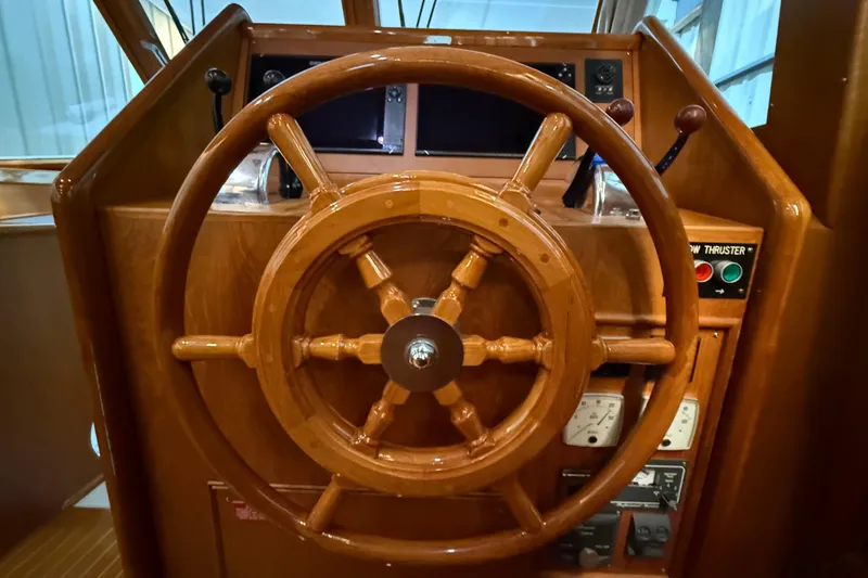 Slide: The Image of Wooden helm of 2000 Grand Banks 43 Eastbay FB yacht, featuring classic nautical controls. - 77