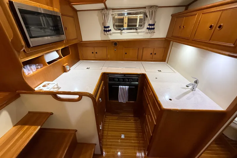 Slide: The Image of Luxurious kitchen interior of 2000 Grand Banks 43 Eastbay FB yacht, featuring wood cabinetry and modern appliances. - 96