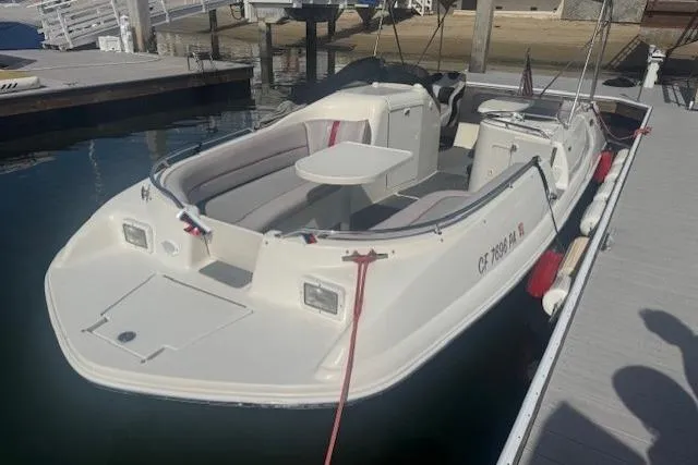 Slide: The Image of 1997 Sea Ray 240 Sundeck boat docked, featuring spacious seating and a central table. - 0