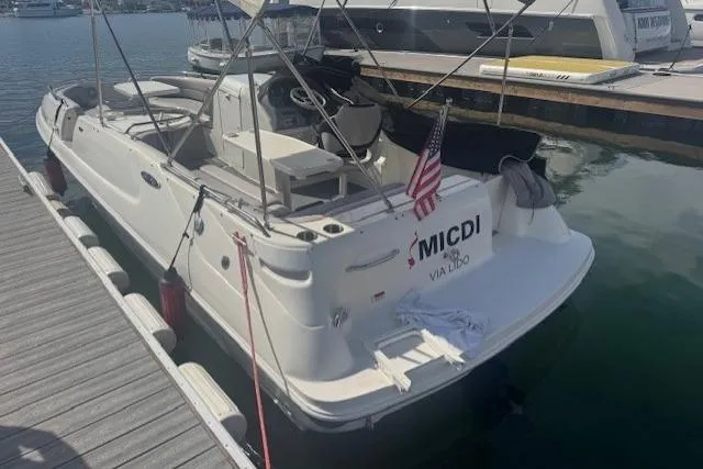 Slide: The Image of 1997 Sea Ray 240 Sundeck docked, featuring a white exterior and American flag. - 3