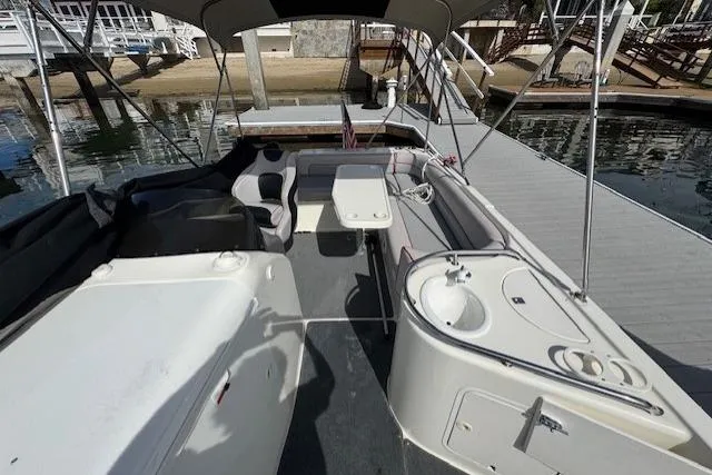 Slide: The Image of 1997 Sea Ray 240 Sundeck boat interior with seating, table, and sink by the dock. - 8