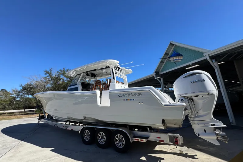 Slide: The Image of 2027 Caymas 401 CC boat on trailer, featuring Yamaha engines, parked outdoors. - 14