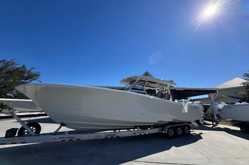Slide: The Image of 2027 Caymas 401 CC boat on trailer under bright sunlit sky. - 2