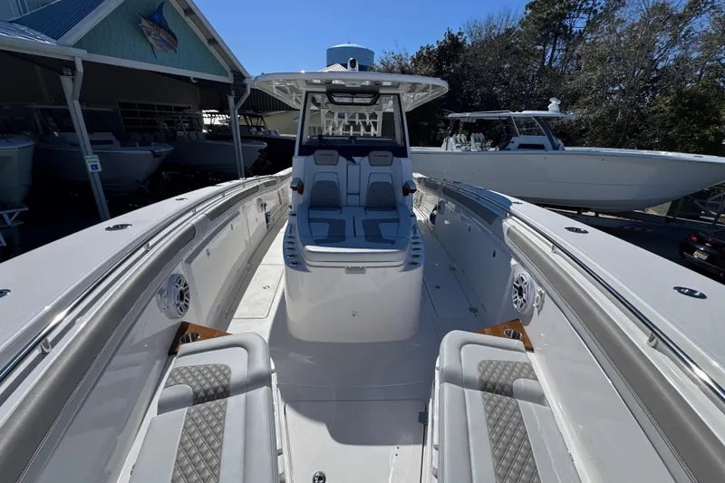 Slide: The Image of 2027 Caymas 401 CC boat interior with seating and console, docked outdoors. - 20