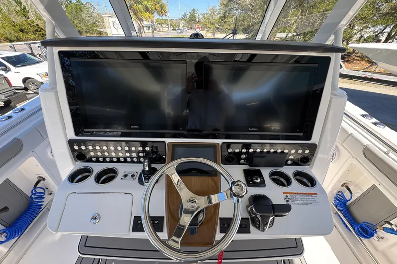 Slide: The Image of 2027 Caymas 401 CC boat helm with dual screens, steering wheel, and control panel. - 39