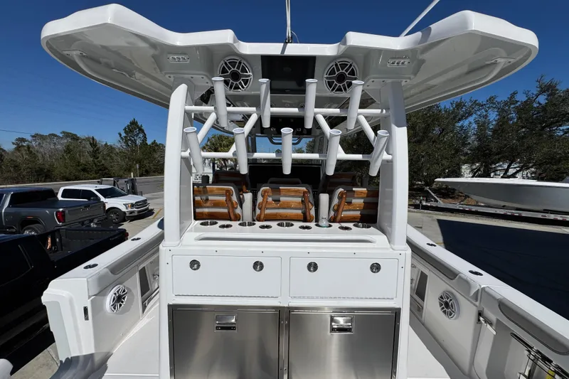 Slide: The Image of 2027 Caymas 401 CC boat interior with rod holders and seating, parked outdoors. - 45