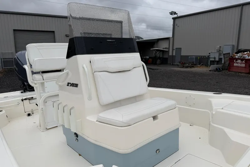 Slide: The Image of 2025 Skeeter SX241 boat interior with white seating and console, parked outdoors. - 17