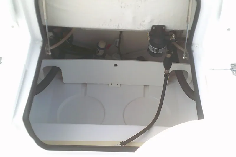 Slide: The Image of 2023 Sportsman Heritage 241 Center Console storage compartment with visible hoses and fittings. - 11