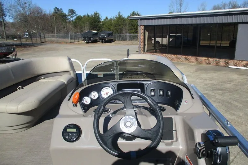 Slide: The Image of 2021 Sun Tracker Party Barge 18 DLX dashboard and seating area in outdoor setting. - 10