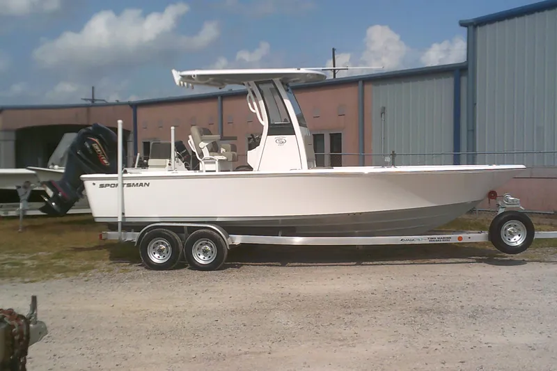 The Image of 2025 Sportsman Masters 227 Bay Boat on trailer, parked outdoors near industrial buildings. - 0
