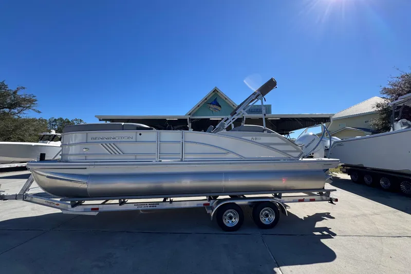 Slide: The Image of 2026 Bennington 22 MSB pontoon boat on trailer under clear blue sky. - 1