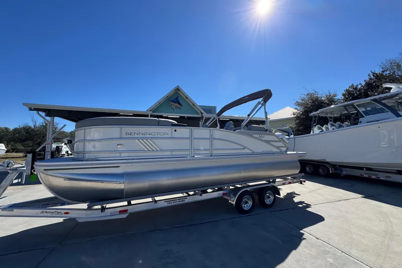 Slide: The Image of 2026 Bennington 22 MSB pontoon boat on trailer under clear blue sky. - 2