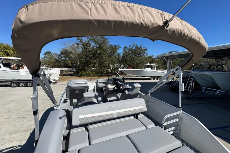 Slide: The Image of 2026 Bennington 22 MSB pontoon boat with canopy, parked outdoors under clear blue sky. - 31