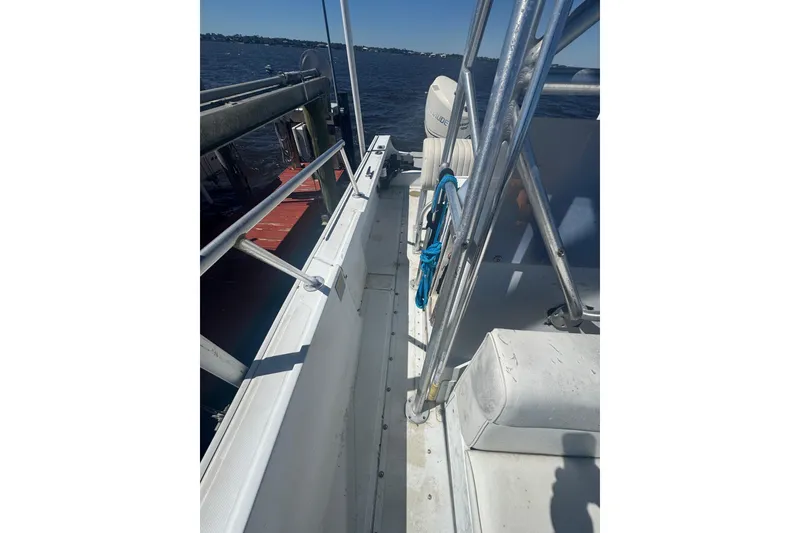 Slide: The Image of 1988 Boston Whaler Outrage 17 boat interior with railing and seating, docked by the water. - 17