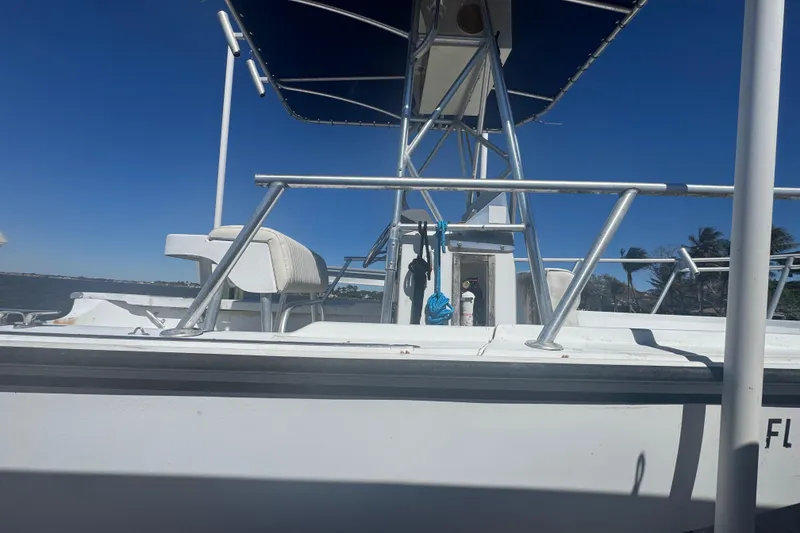 Slide: The Image of 1988 Boston Whaler Outrage 17 boat with blue canopy, docked by the water. - 2