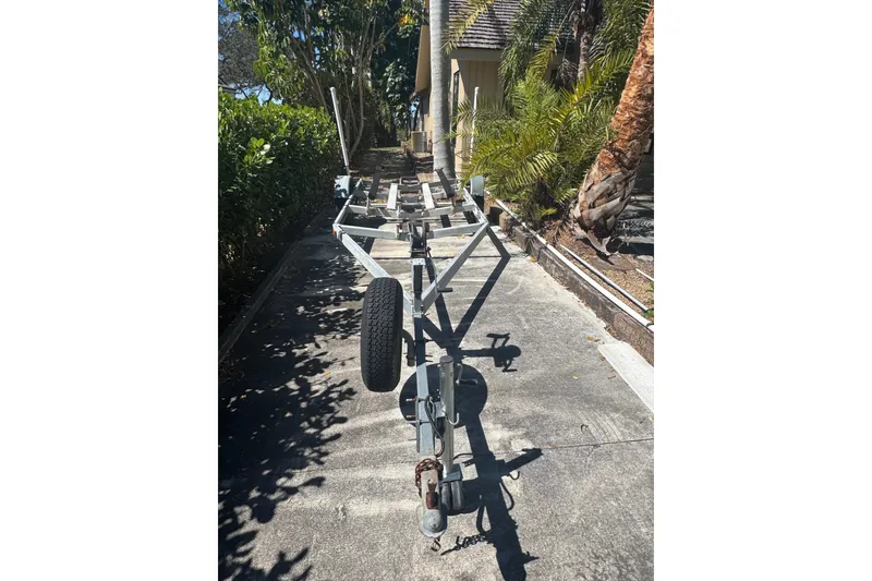 Slide: The Image of Empty boat trailer for 1988 Boston Whaler Outrage 17, parked on a sunny driveway. - 31