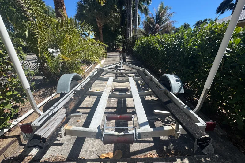 Slide: The Image of Boat trailer for 1988 Boston Whaler Outrage 17, parked on a sunny, palm-lined street. - 32
