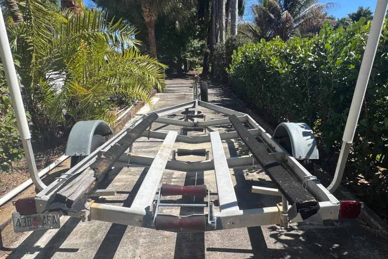 Slide: The Image of Empty boat trailer for 1988 Boston Whaler Outrage 17, surrounded by lush greenery. - 34